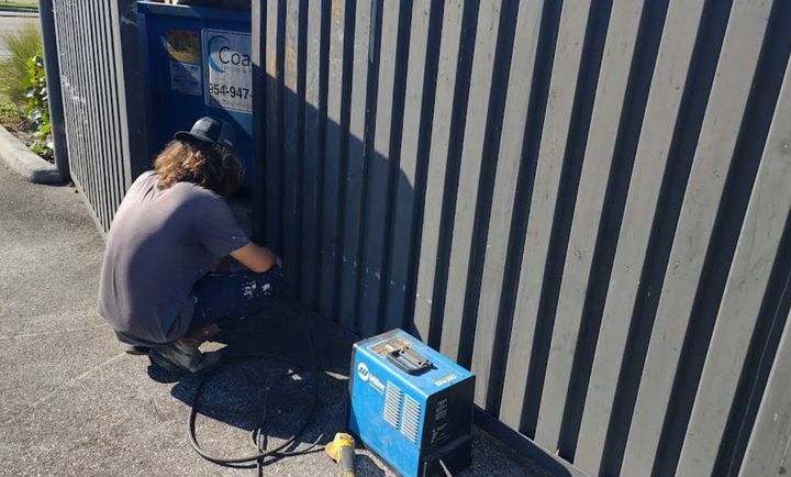 Crew member welding a metal dumpster enclosure